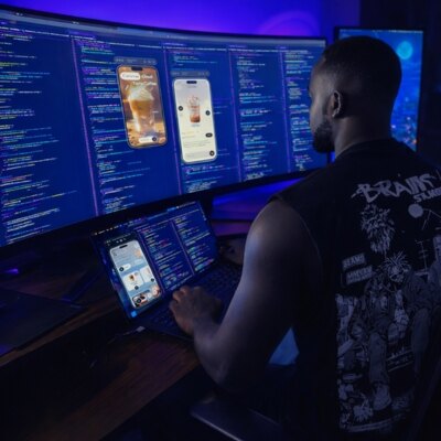 Claude O. Berko working at a multi-monitor development workstation
